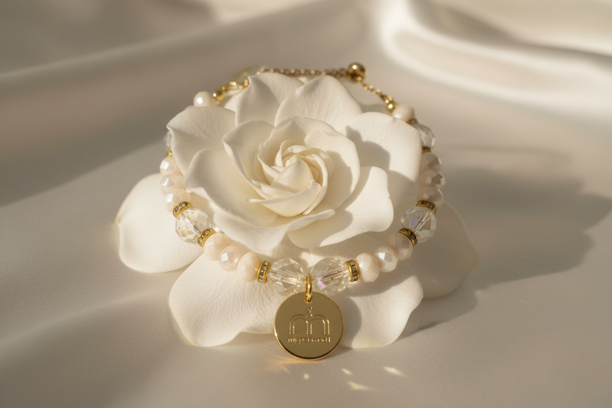 Collana Ivory Glow con cristalli sfaccettati avorio, cristalli trasparenti e ciondolo logo dorato fotografata su una rosa bianca – My Pets and I Milano