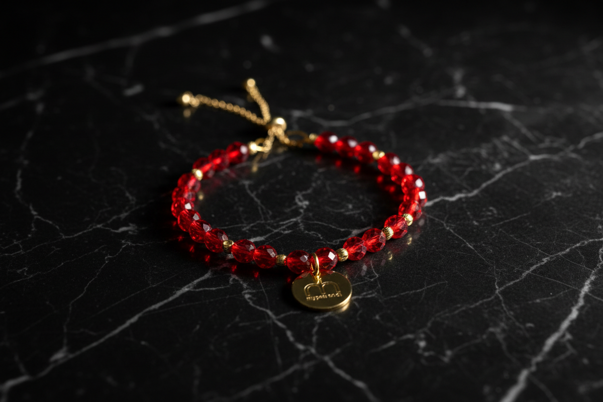 Collana Ruby Glow con cristalli rossi sfaccettati e ciondolo logo dorato fotografata su una superficie in marmo nero – My Pets and I Milano