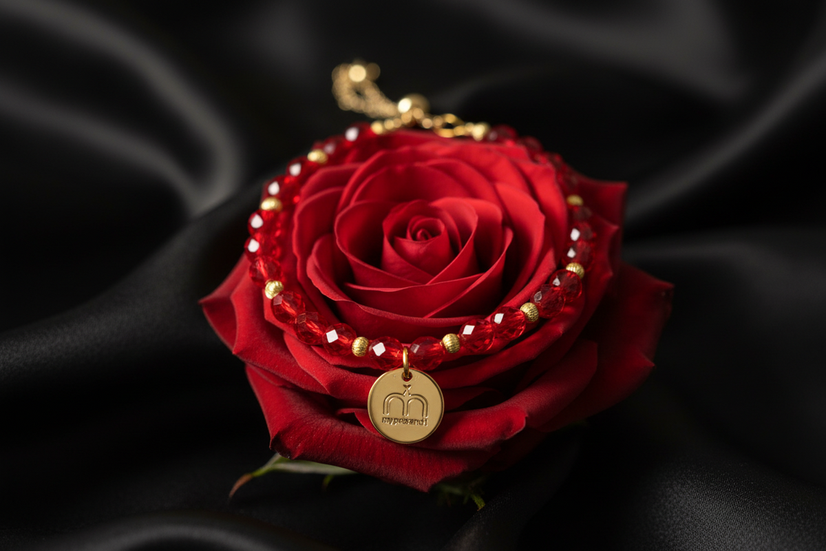 Collana Ruby Glow con cristalli rossi sfaccettati e ciondolo logo dorato fotografata su una rosa rossa – My Pets and I Milano