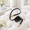 Guinzaglio nero con finiture oro su pouf bianco