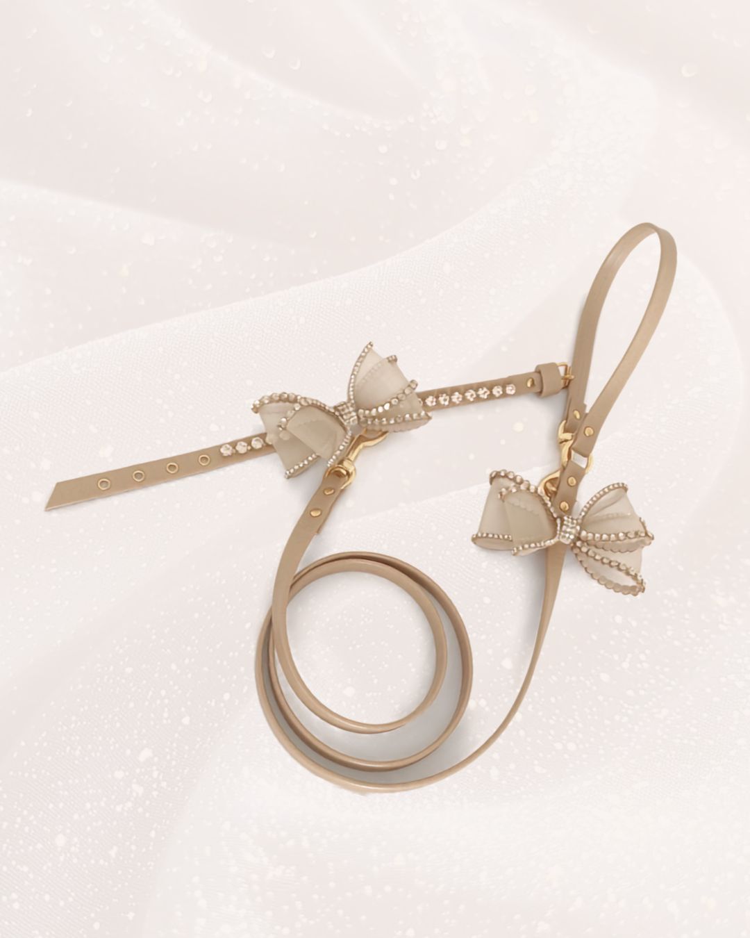 collare per cani con fiocco gioiello strass e guinzaglio coordinato con fiocco gioiello, dettagli colore oro appoggiato su tessuto bianco